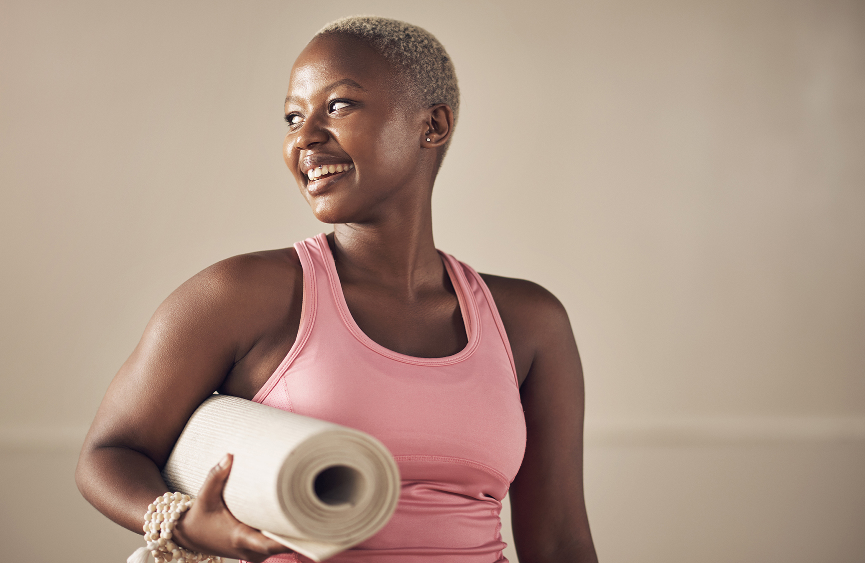 Cropped shot of an attractive young woman standing alone and holding her yoga mat before an indoor yoga session