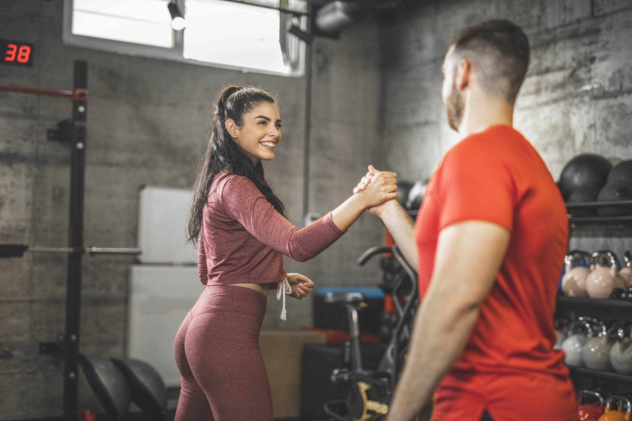 Young woman and man are shaking hands after an intense training in the gym. Focus on woman