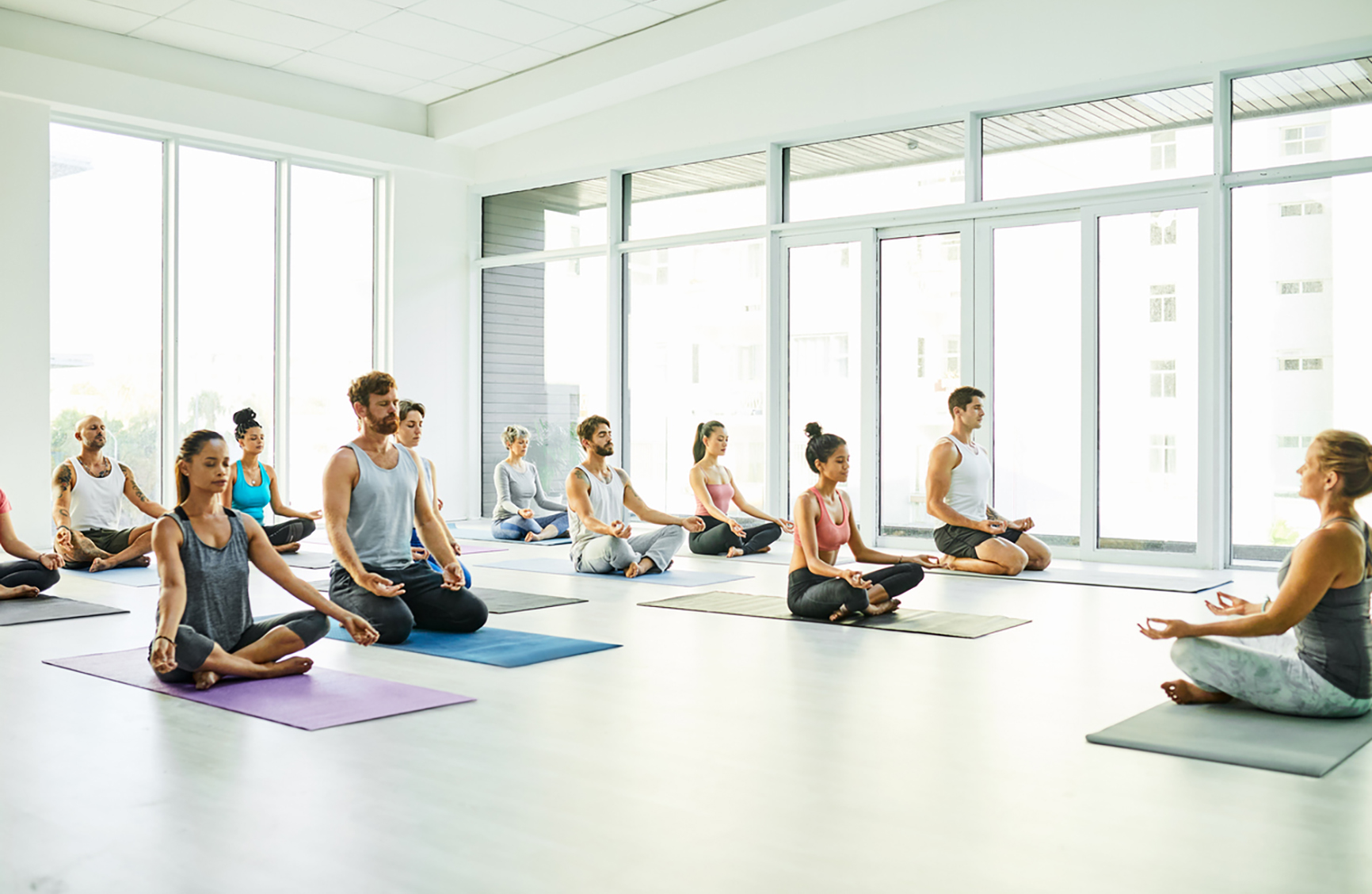 Shot of a group of men and women meditating in the lotus position during a yoga class