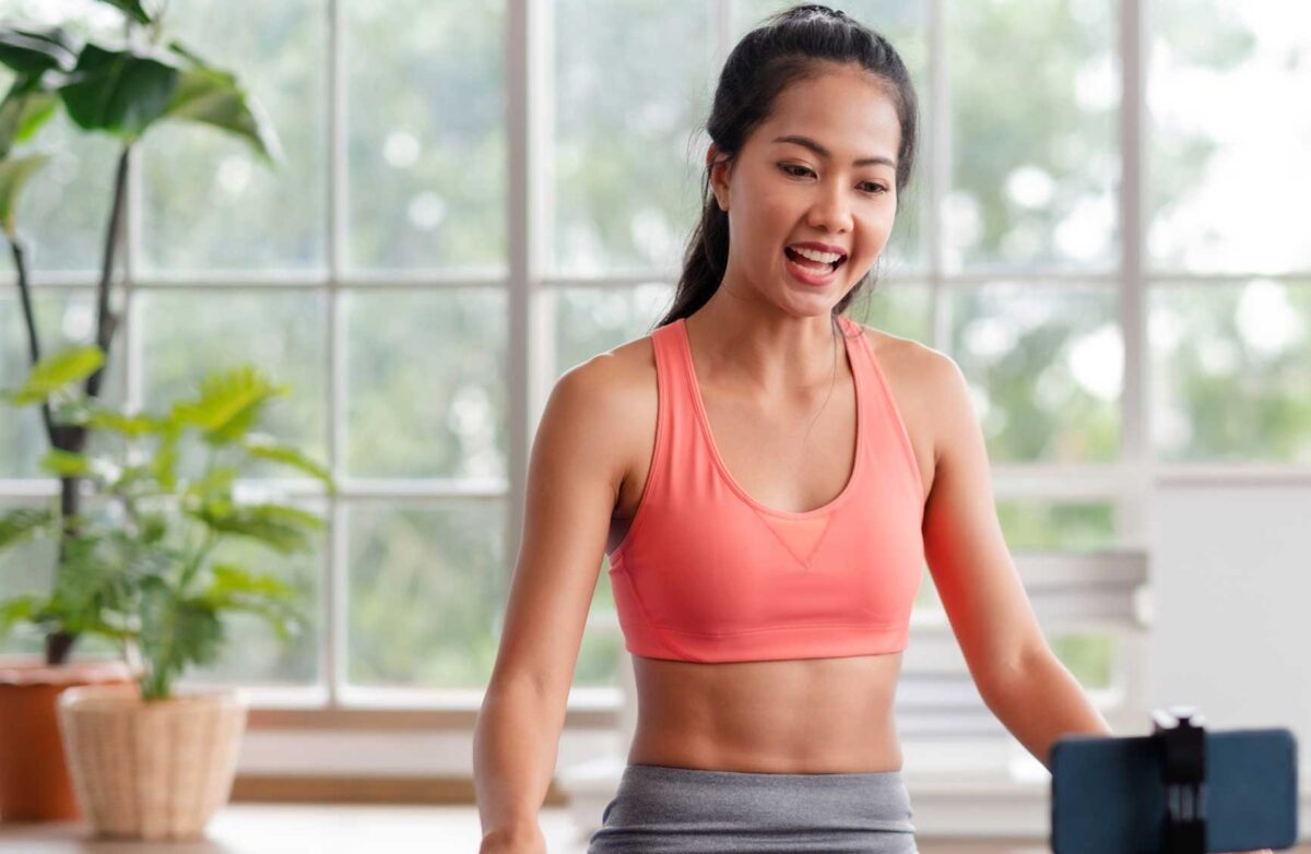 asian trainer woman live streaming on social media about wellness exercise at home.Influrencer marketing trainning course online.new normal fitness class