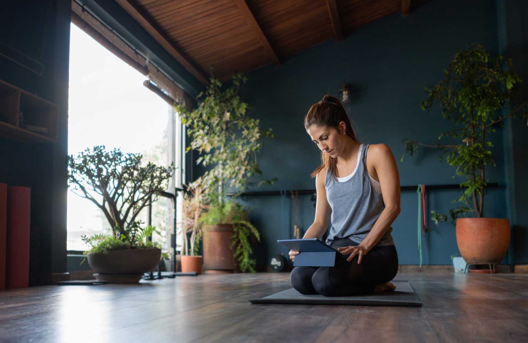 Latin American woman setting up a tablet computer to stream an online yoga class from a wellness center