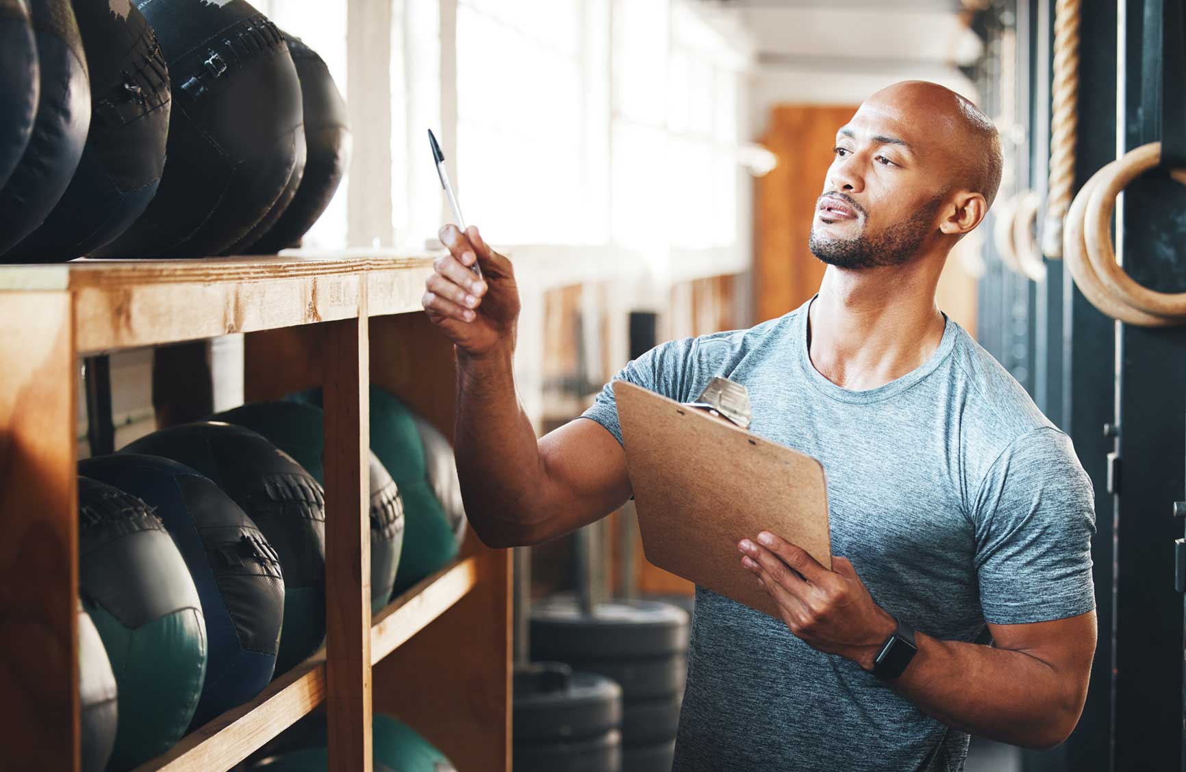 Shot of a muscular young man using a clipboard while checking equipment in a gym