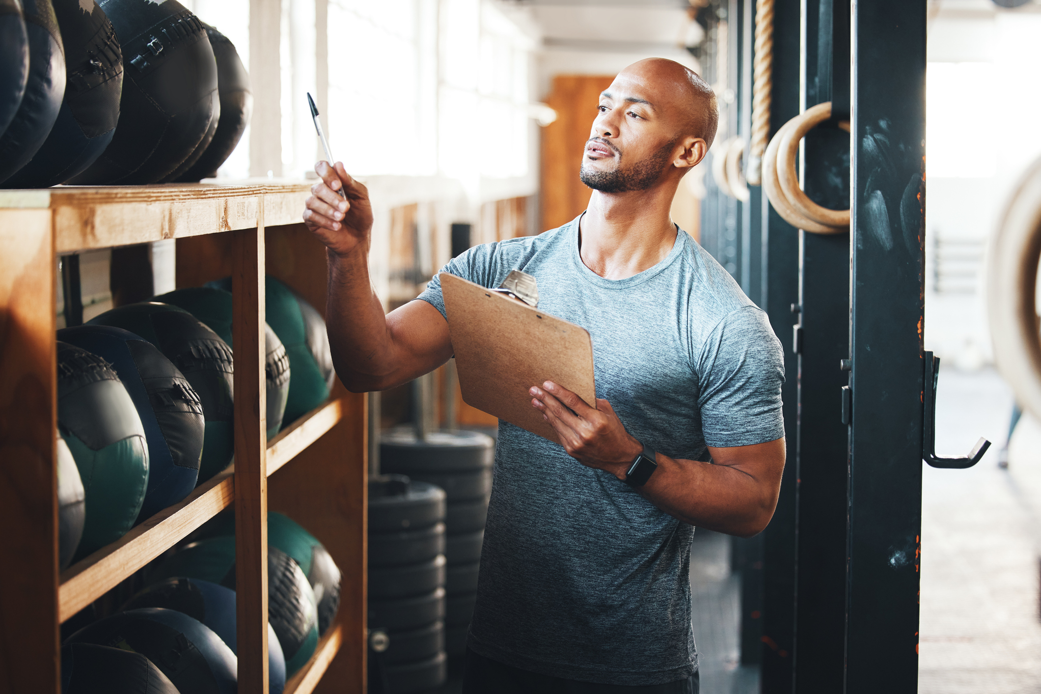 Shot of a muscular young man using a clipboard while checking equipment in a gym