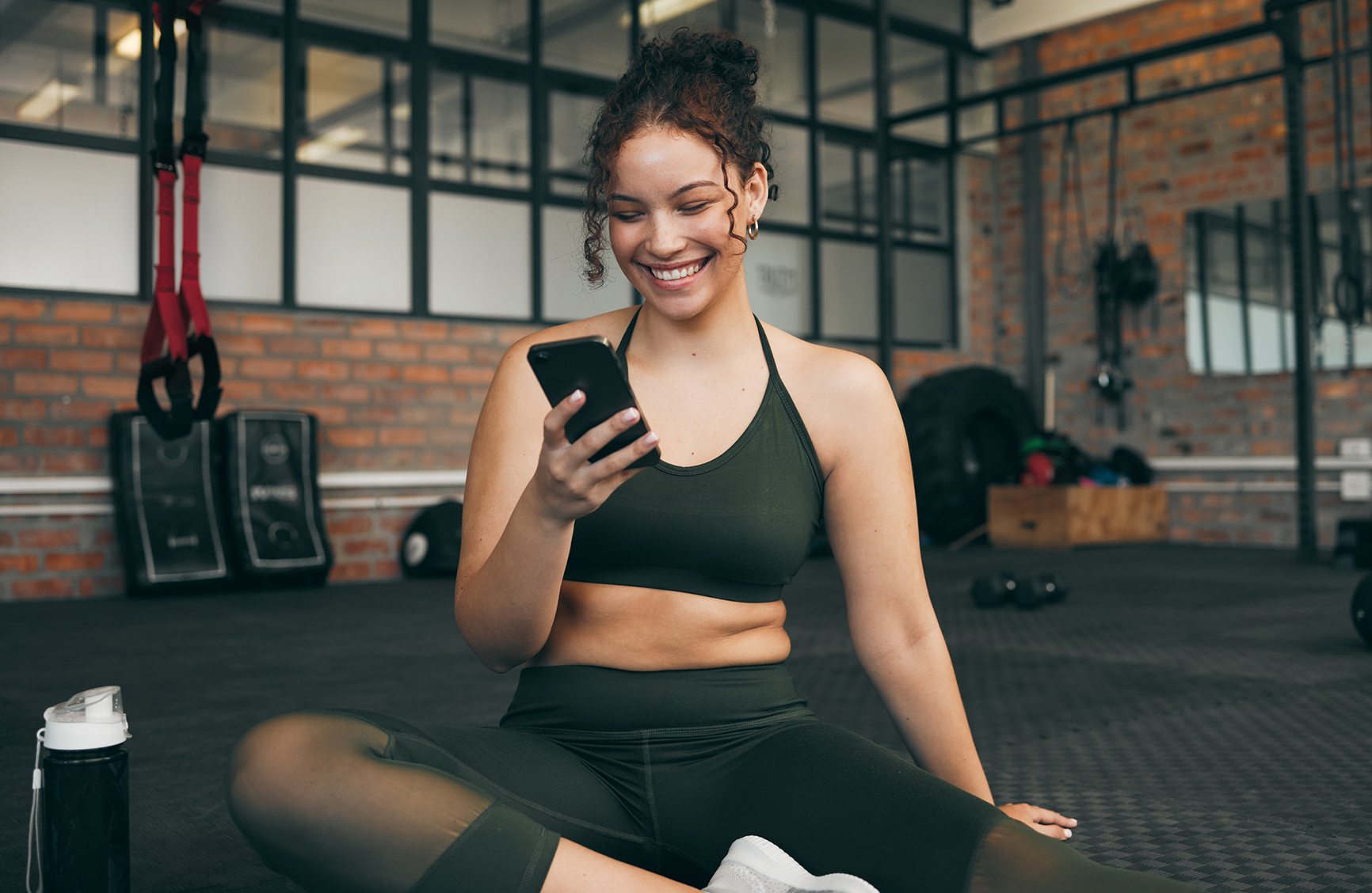 Happy woman, fitness and phone at gym for a workout, training and body wellness with a mobile app. Sports female with smartphone for progress, performance and communication for a healthy lifestyle