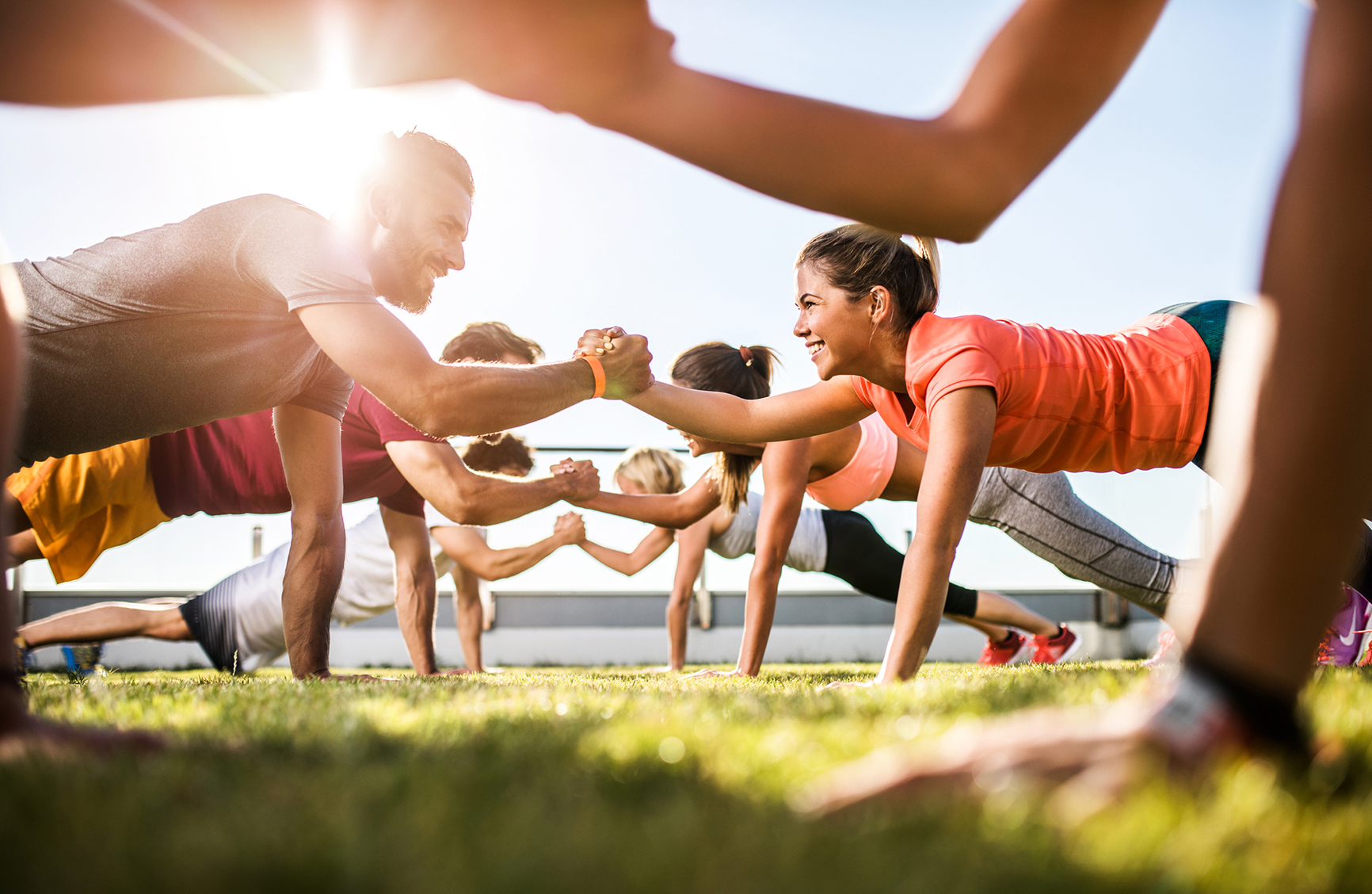 Low angle view of athletes cooperating while exercising on a sports training outdoors. Focus is happy couple.