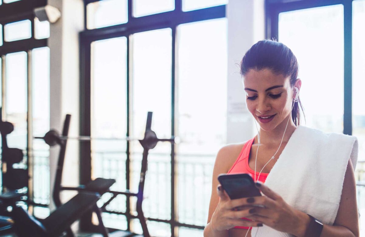 Young hispanic woman with smartwatch and smartphone checking heart rate on fitness tracker application