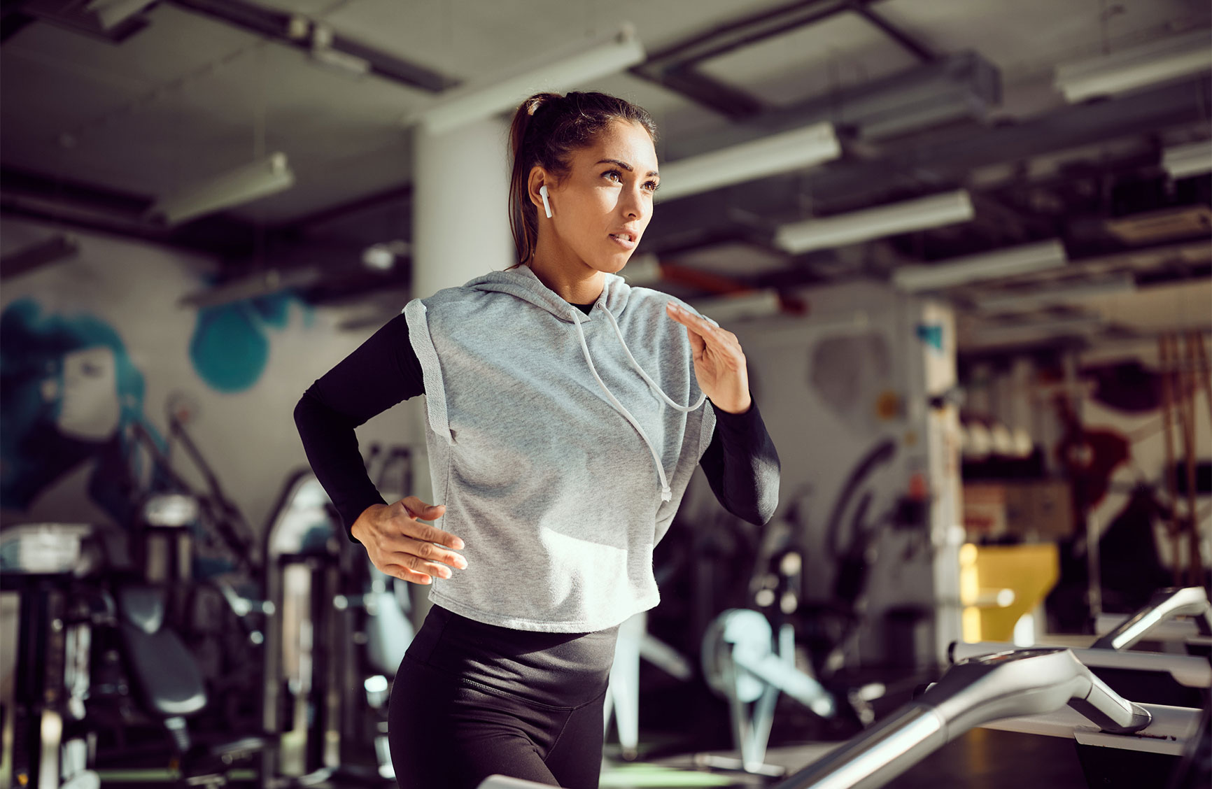 Young female runner exercising on treadmill in a gym.