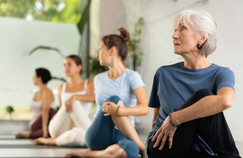 Group of sporty people practicing various yoga positions during training indoors