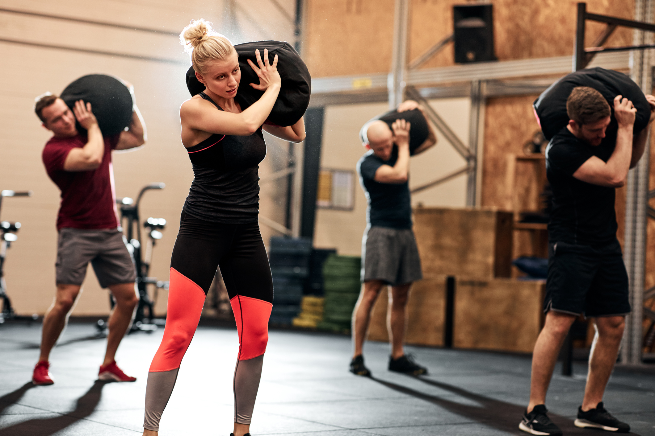 Fit group of people working out with weight bags during a strength training class in a gym