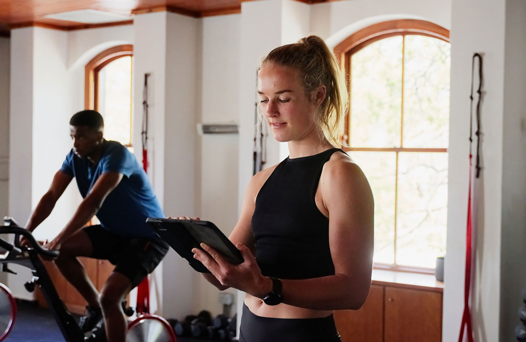 Professional young caucasian woman in sportswear using digital tablet at the gym