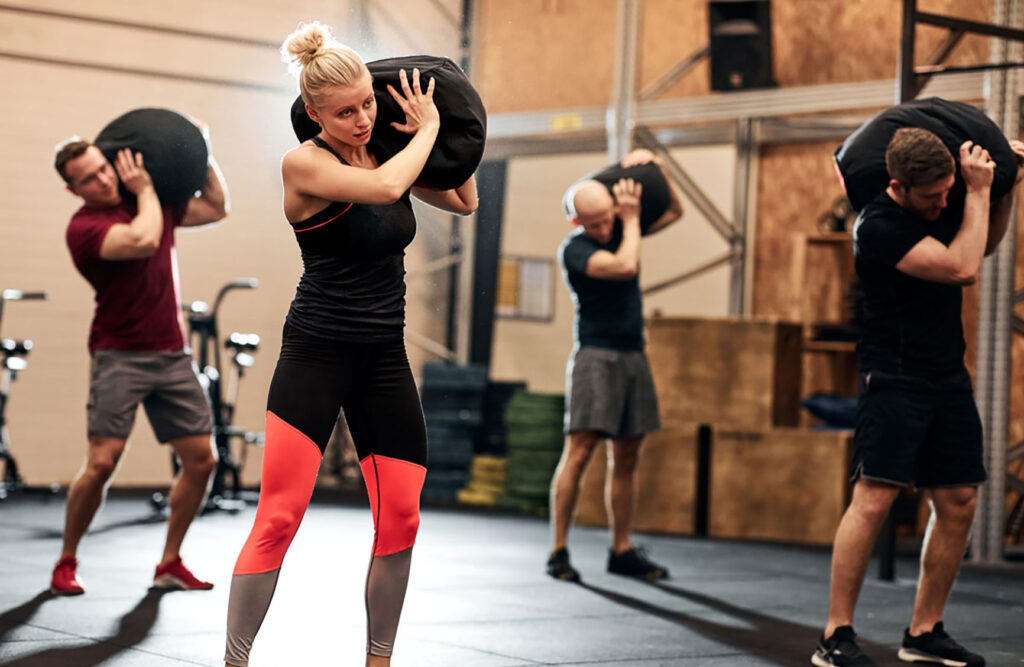 Fit group of people working out with weight bags during a strength training class in a gym