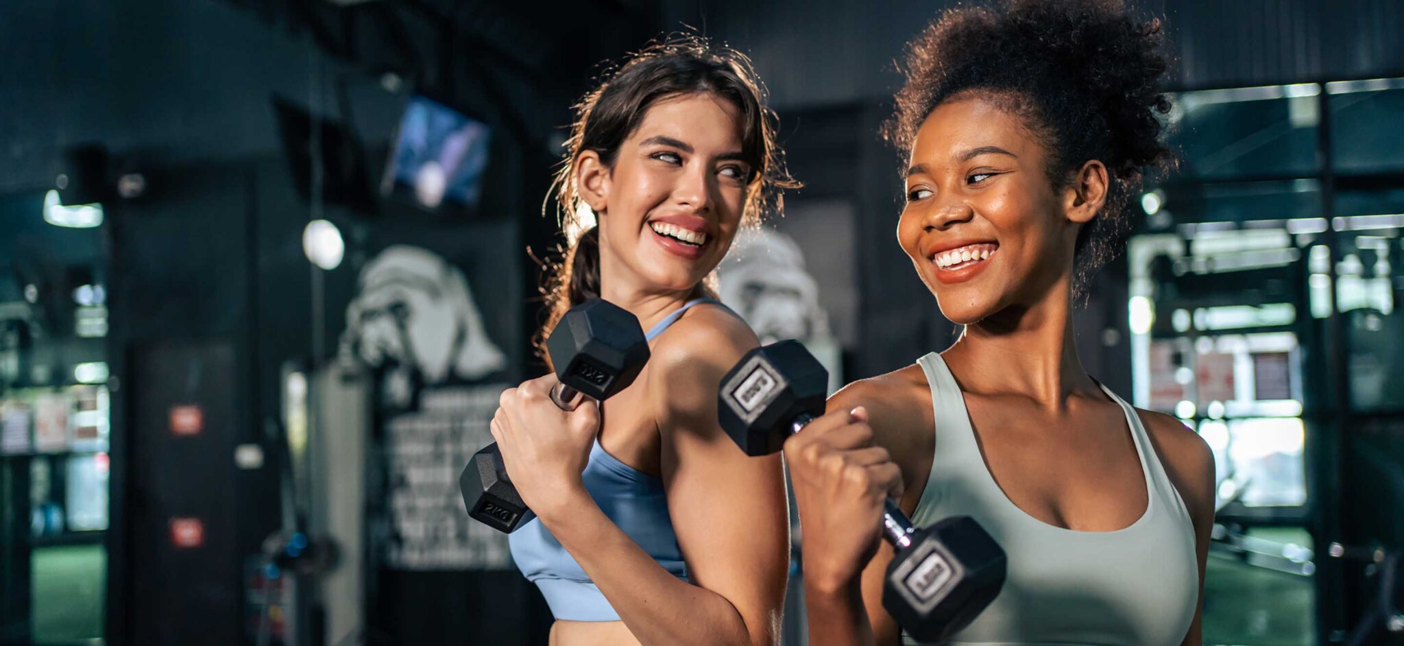 two girls lifting weights and smiling
