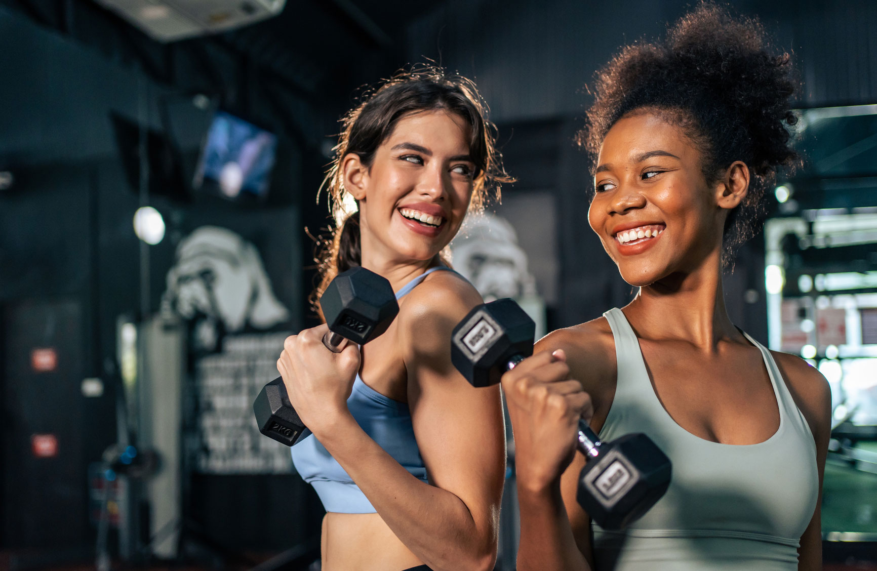 two girls lifting weights and smiling