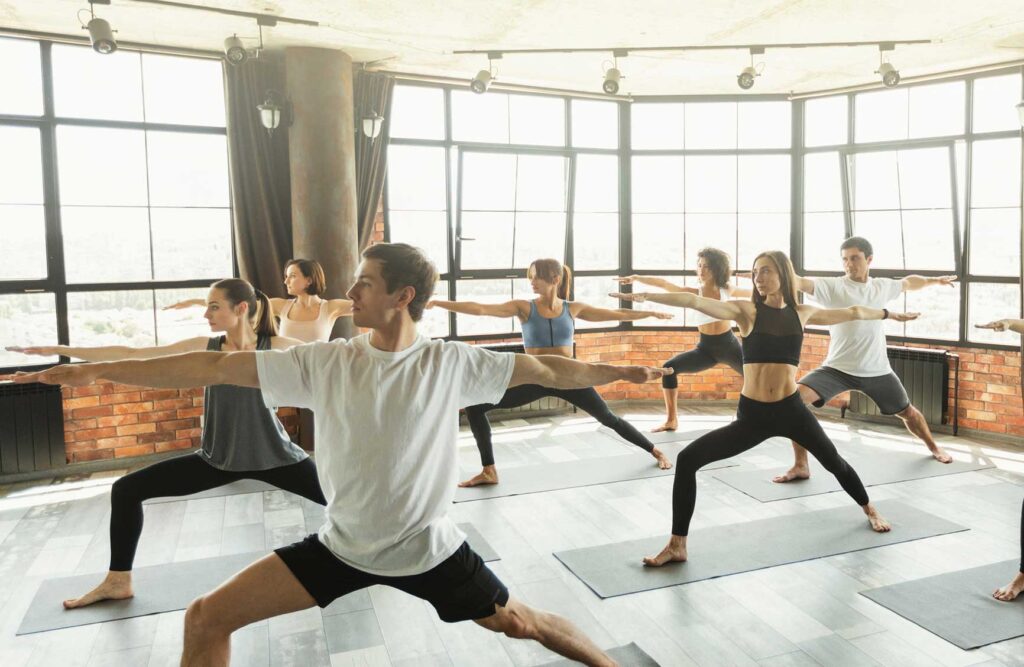 A group of students in a 500 our YTT certification course doing the warrior pose.