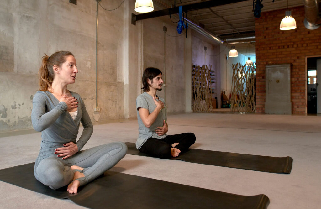 A man and a woman sitting on their yoga mats in a minimalistic zen studio