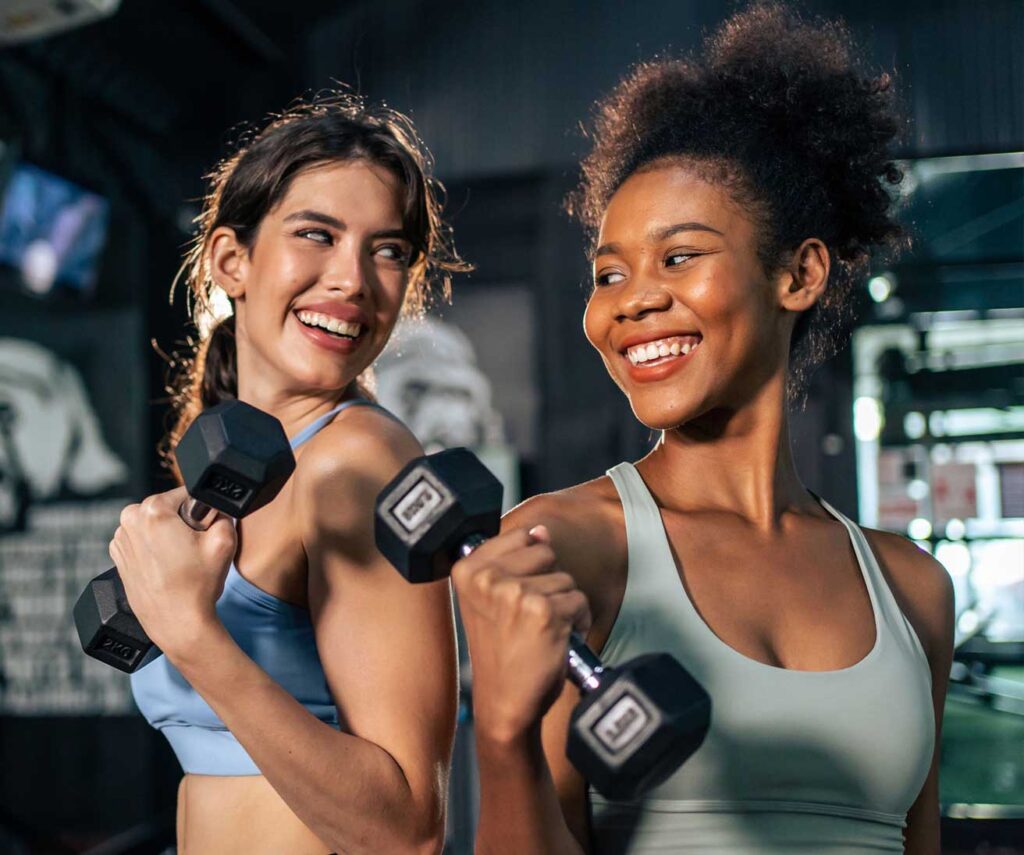 Two ladies in a gym with dumbells