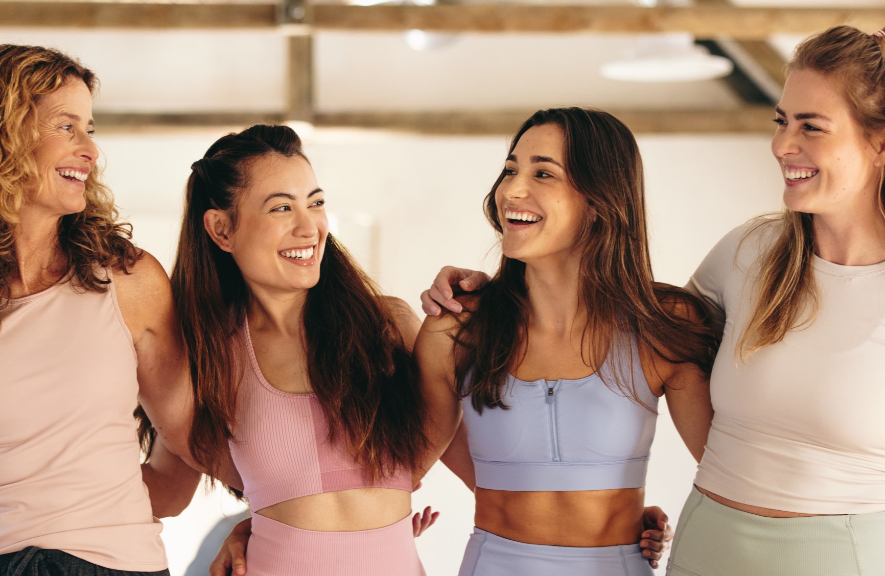 Four smiling ladies in gym wear in a studio.